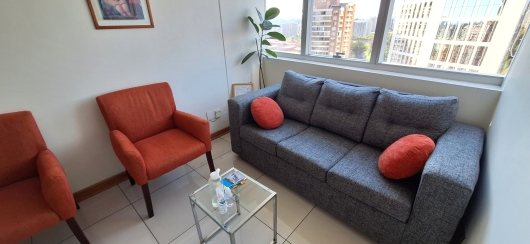Consulta de psicología en Las Condes: sillón y sofá junto a ventanal